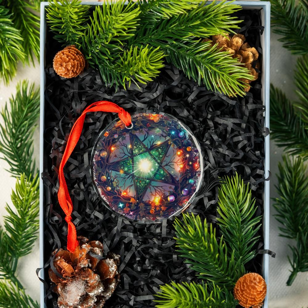 Clear glass pentagram ornament with colorful lights, red ribbon, in a gift box with pine branches and cones.