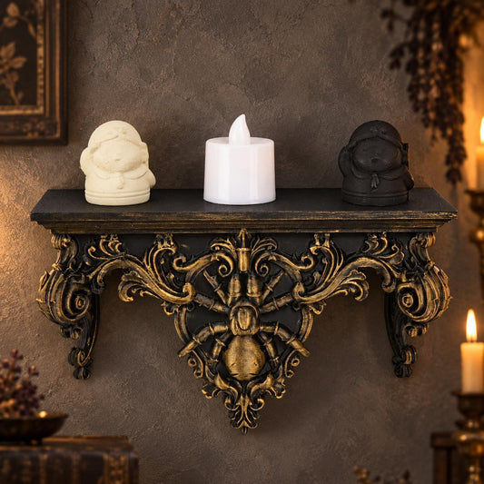 Black and gold baroque spider shelf styled with two figurines and a candle against a gothic wall
