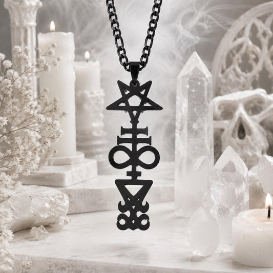 Black Inverted Pentagram Cross sigil pendant necklace on black chain, styled with white candles, quartz crystal points, dried flowers, and a small skull