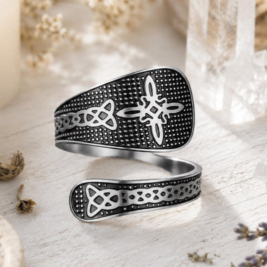 Silver Witch Knot open ring with black textured band and Celtic trinity knot engraving, displayed on rustic wood with dried lavender and crystal