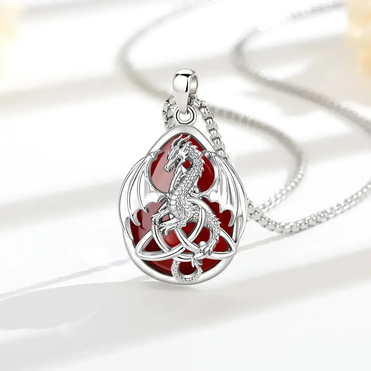 Carnelian Celtic dragon necklace arranged on a sunlit white display surface