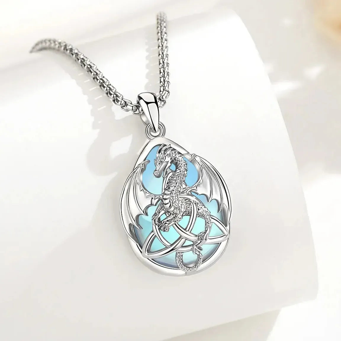 Moonstone dragon pendant with Celtic knotwork hanging over a white display block