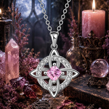 Pink crystal Celtic Witch Knot pendant necklace with silver chain, surrounded by witchcraft altar items like candles and crystals