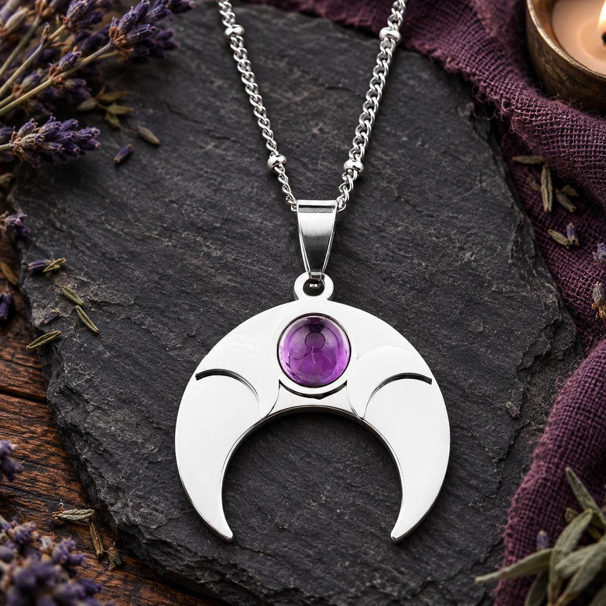 Silver-tone amethyst crescent moon pendant necklace on a witchy altar
