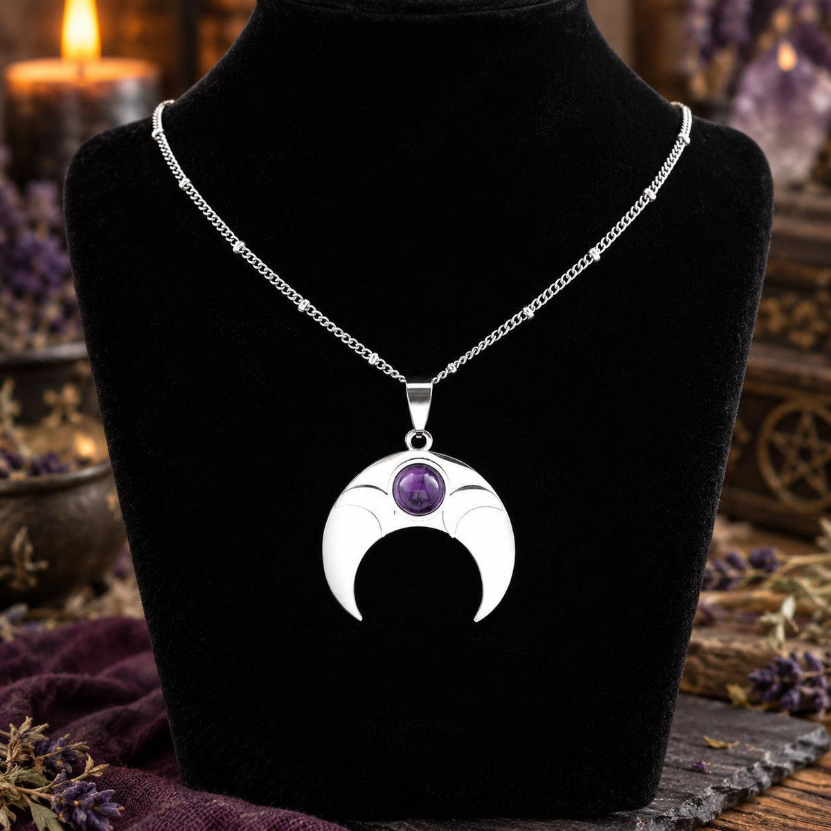 Amethyst crescent moon necklace displayed on a black jewelry bust in a witchy altar setting