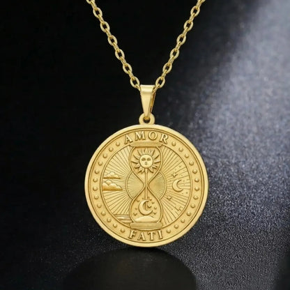 Gold-tone Amor Fati hourglass medallion necklace on a dark surface
