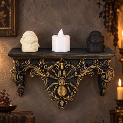 Black and gold baroque spider shelf styled with two figurines and a candle against a gothic wall