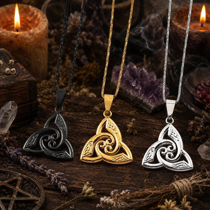Three color options of Celtic triquetra trinity knot pendant necklace - black, gold, and silver - hanging together on rustic wooden altar with lit candles, pentagram, and dried lavender