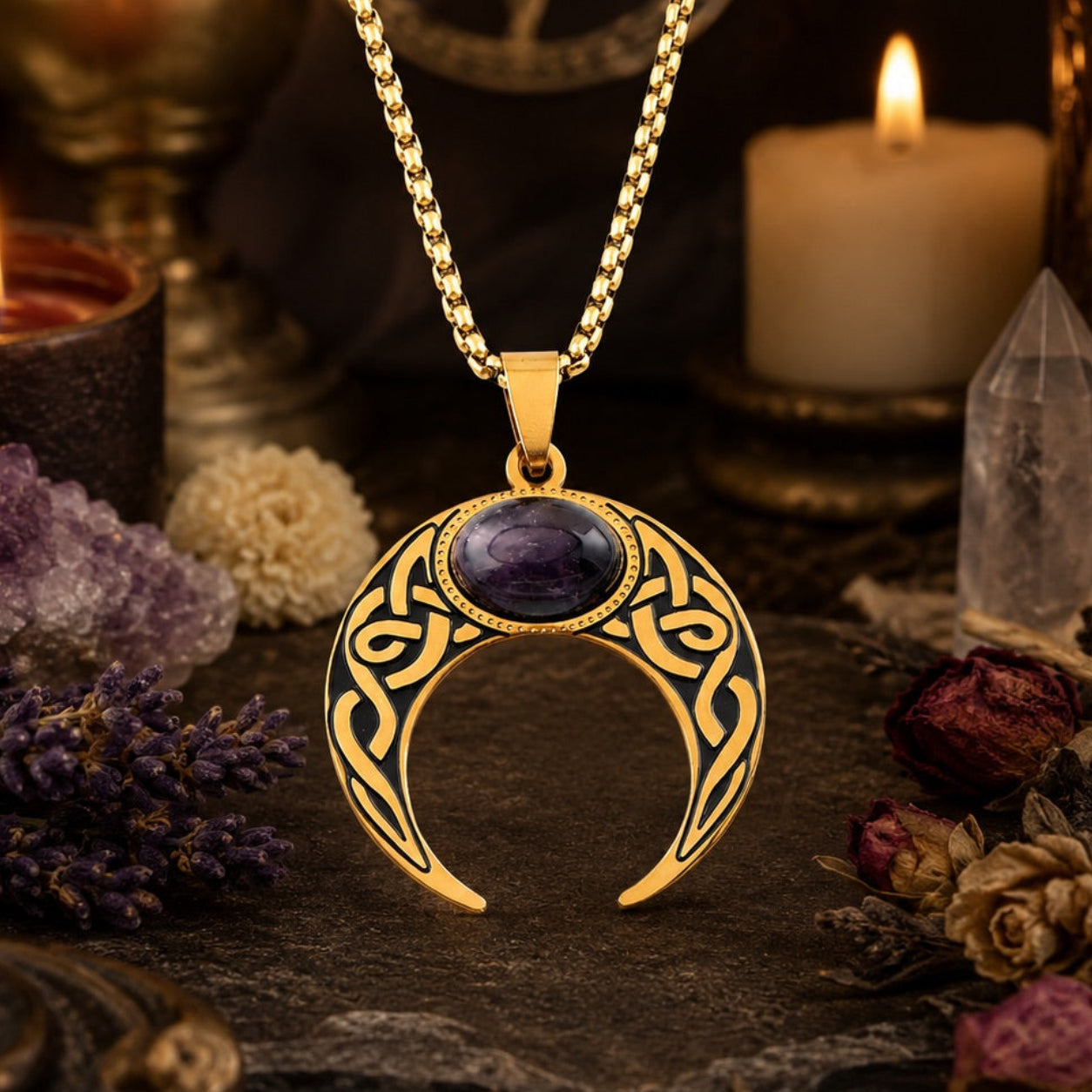 Close-up of gold Celtic knot crescent moon necklace with oval amethyst cabochon pendant, styled with amethyst clusters, a clear quartz point, dried flowers, and a lit candle