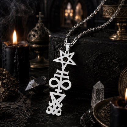 Silver Inverted Pentagram Cross sigil pendant necklace on rope chain, resting on a dark textured box with a lit candle, quartz crystal points, and ornate gothic urns