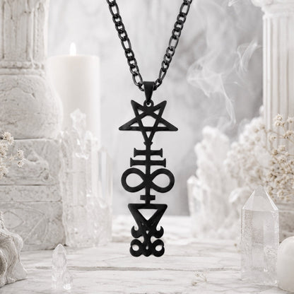 Black Inverted Pentagram Cross sigil pendant necklace on black chain, hanging in front of white marble pillars with a candle and quartz crystal points
