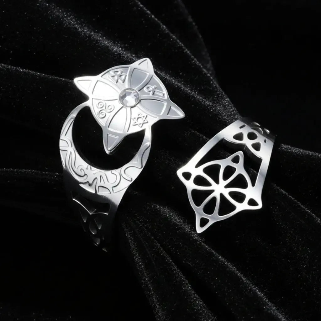 Silver crescent moon witch ring close-up on dark satin, showing the celtic knotwork cutout, engraved lunar band, and star medallion set with a clear stone.