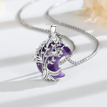 Alternate tree pendant on pale fabric: Crescent Moon Tree of Life Necklace, featuring a branching tree of life over a crescent-shaped stone.