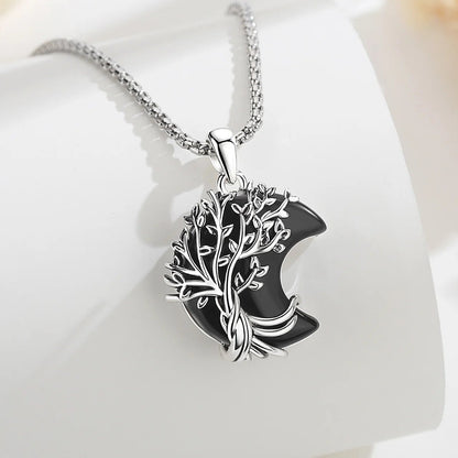 Necklace chain detail on pale fabric: Crescent Moon Tree of Life Necklace, featuring a branching tree of life over a crescent-shaped stone.