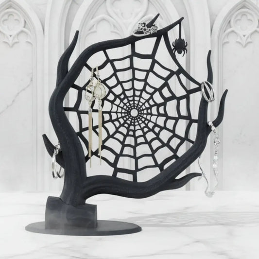 Black spider web jewelry stand with earrings on a white background