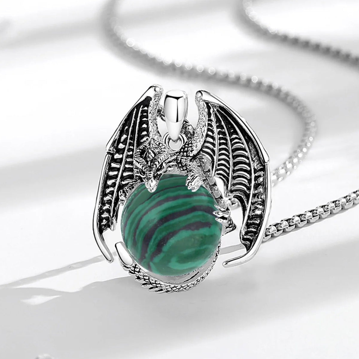 Dragon pendant on pale fabric: Dragon Malachite Ball Pendant Necklace, featuring a winged dragon holding a round malachite stone.