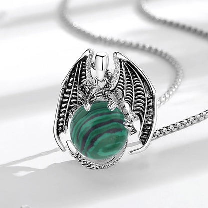 Dragon pendant on pale fabric: Dragon Malachite Ball Pendant Necklace, featuring a winged dragon holding a round malachite stone.