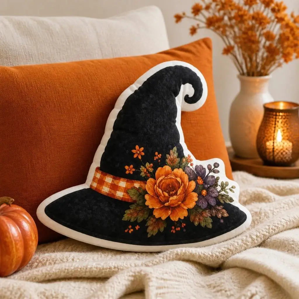 Styled on a sofa: decorative plush pillow featuring witch hat with autumn flowers and stars