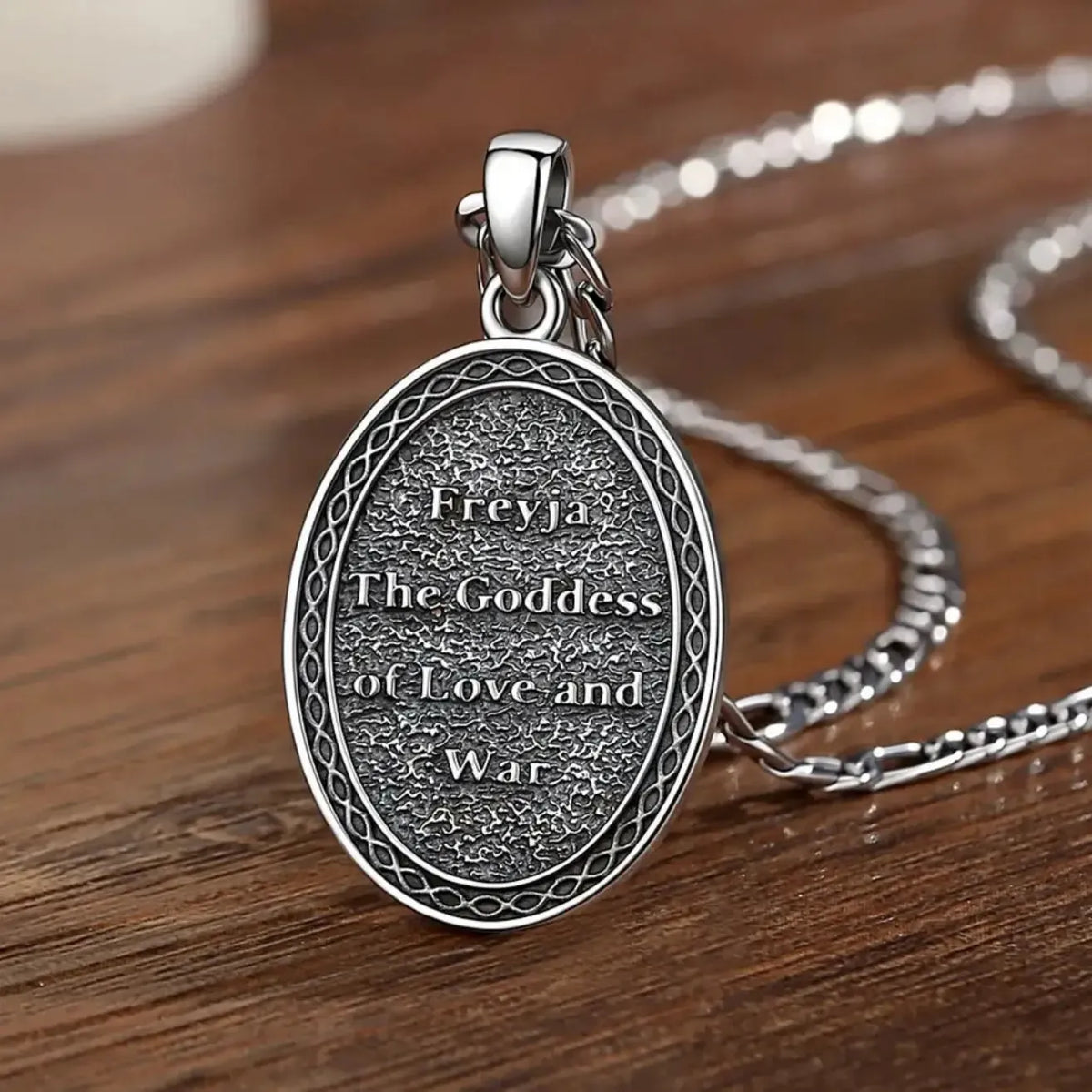 Inscribed reverse of Freya pendant on a wood table