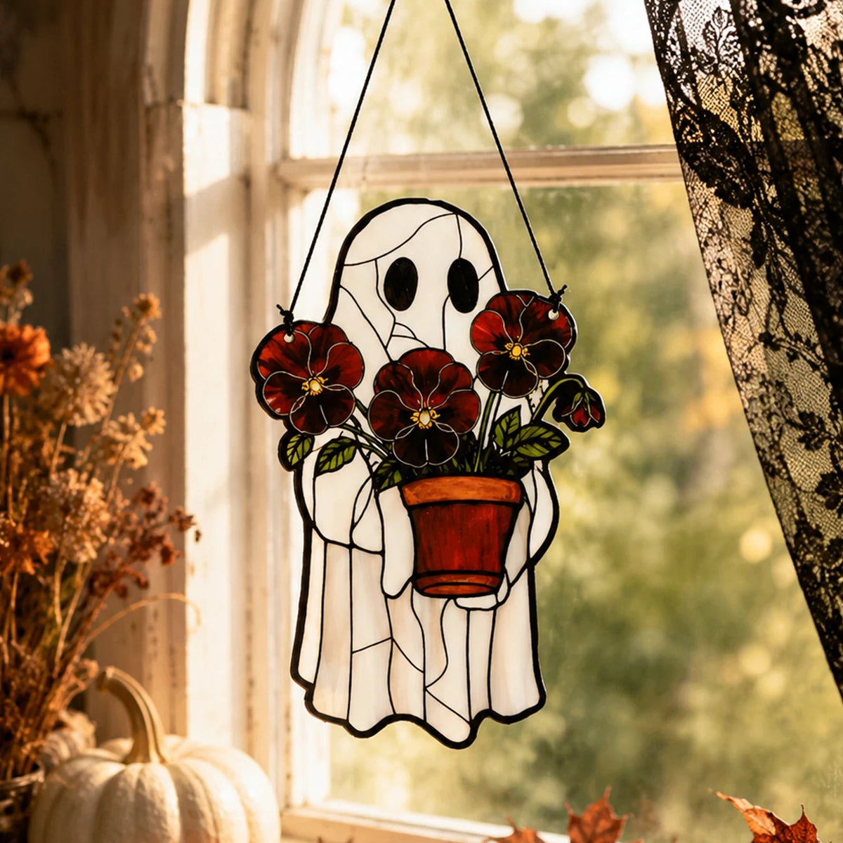 Cute ghost suncatcher hanging among houseplants in a window