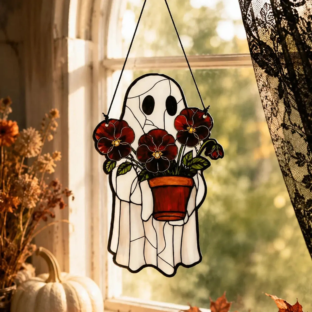 Cute ghost suncatcher hanging among houseplants in a window