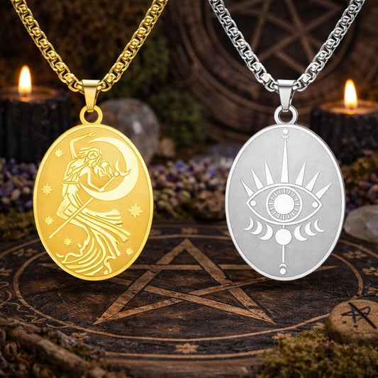 Gold Moon Goddess and silver Eye of Providence oval pendants on chains, on a dark wooden pentagram surface.