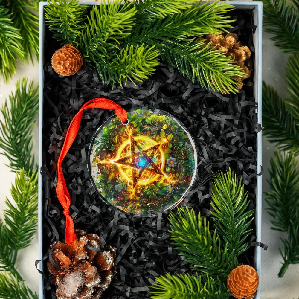 Clear glass pentagram ornament with glowing center, red ribbon, in a gift box with pine needles and cones.