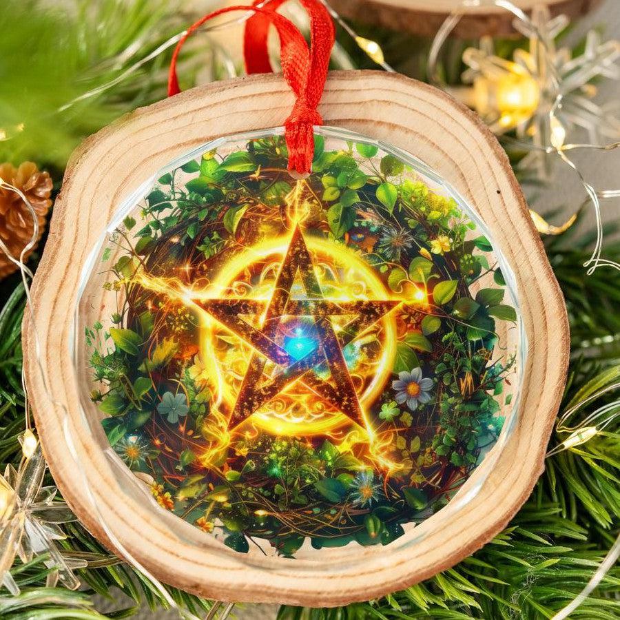 Clear glass pentagram ornament with a glowing star design, red ribbon, and wood slice frame on a Yule tree.