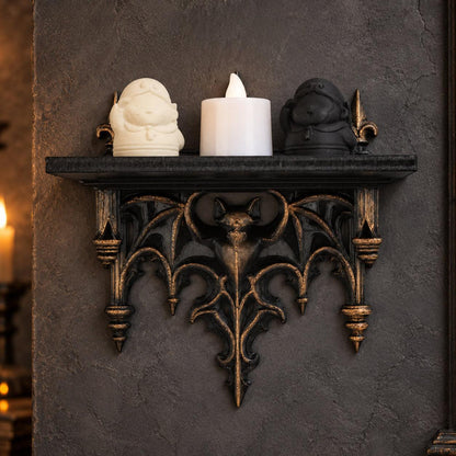 Black and gold bat gargoyle shelf with two figurines and a candle against a gothic wall