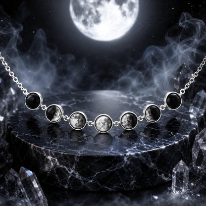 A silver necklace with seven round moon-phase style gemstones displayed on a dark marble pedestal, with a full moon and smoky atmospheric background.