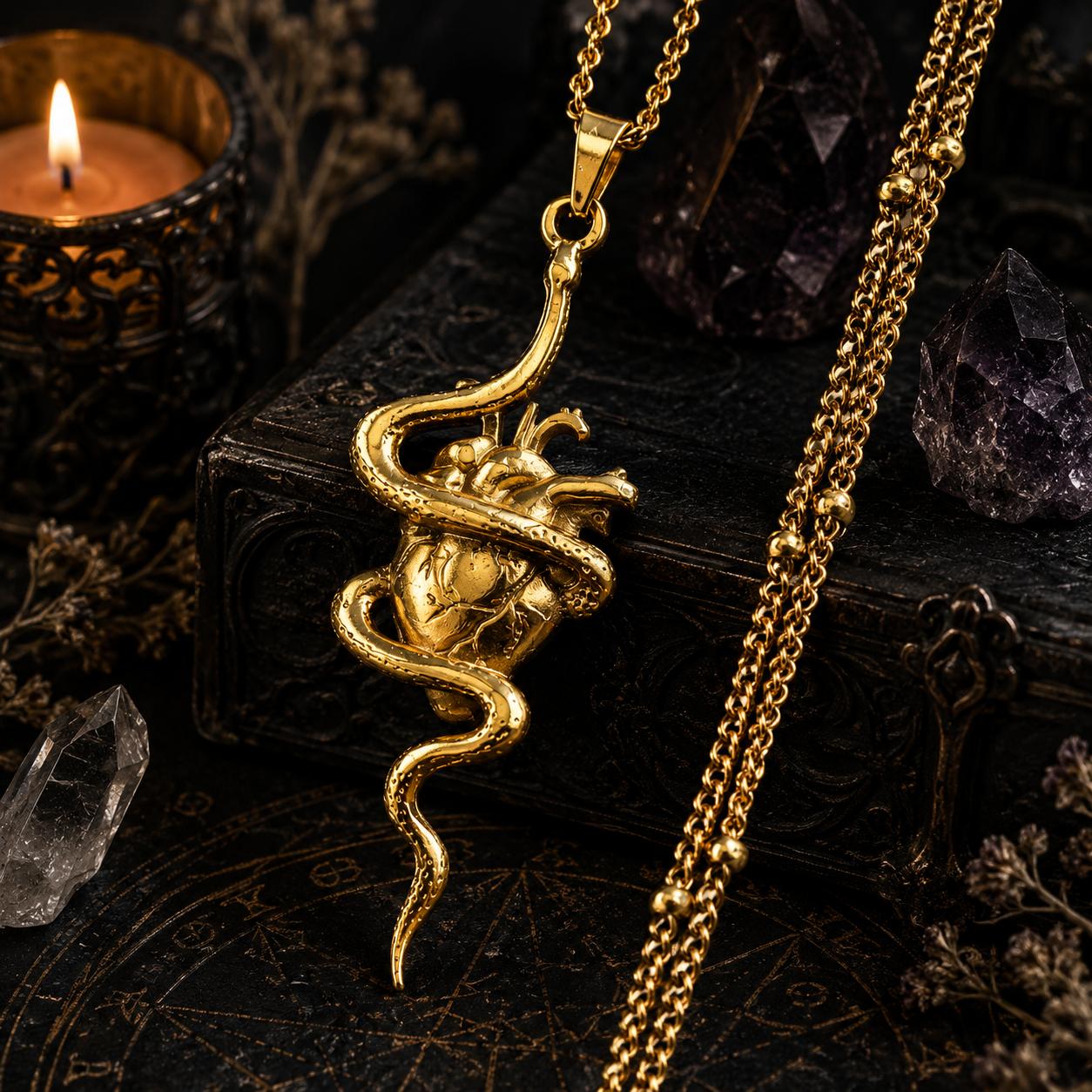 Gold snake pendant necklace on a dark background with candles and crystals.