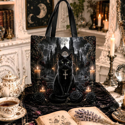 A black tote bag featuring a gothic illustration of a black cat in a dark castle, styled in a cozy, vintage-inspired room with candles, books, and a teapot.