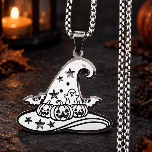 Silver Gothic Witch Hat Necklace with pumpkin, ghost, bat and star details on a dark candlelit stone background.