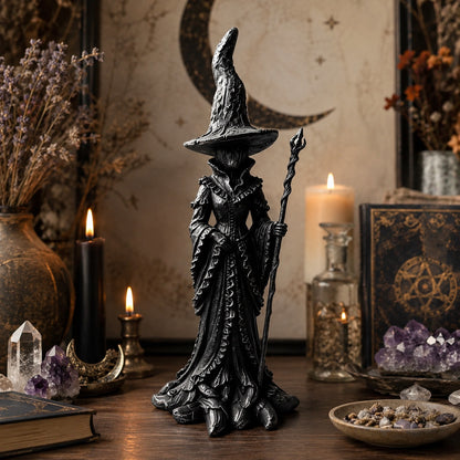 Gothic witch statue near spellbook with pentagram and amethyst crystals