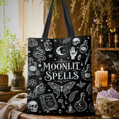 Moonlit Spells black tote bag with moon, eye, crystals, skull, snake, moth, and Book of Spells illustrations