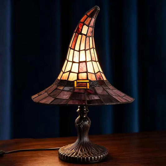 Tiffany-style lamp with stained glass shade on a wooden table against a dark blue curtain background