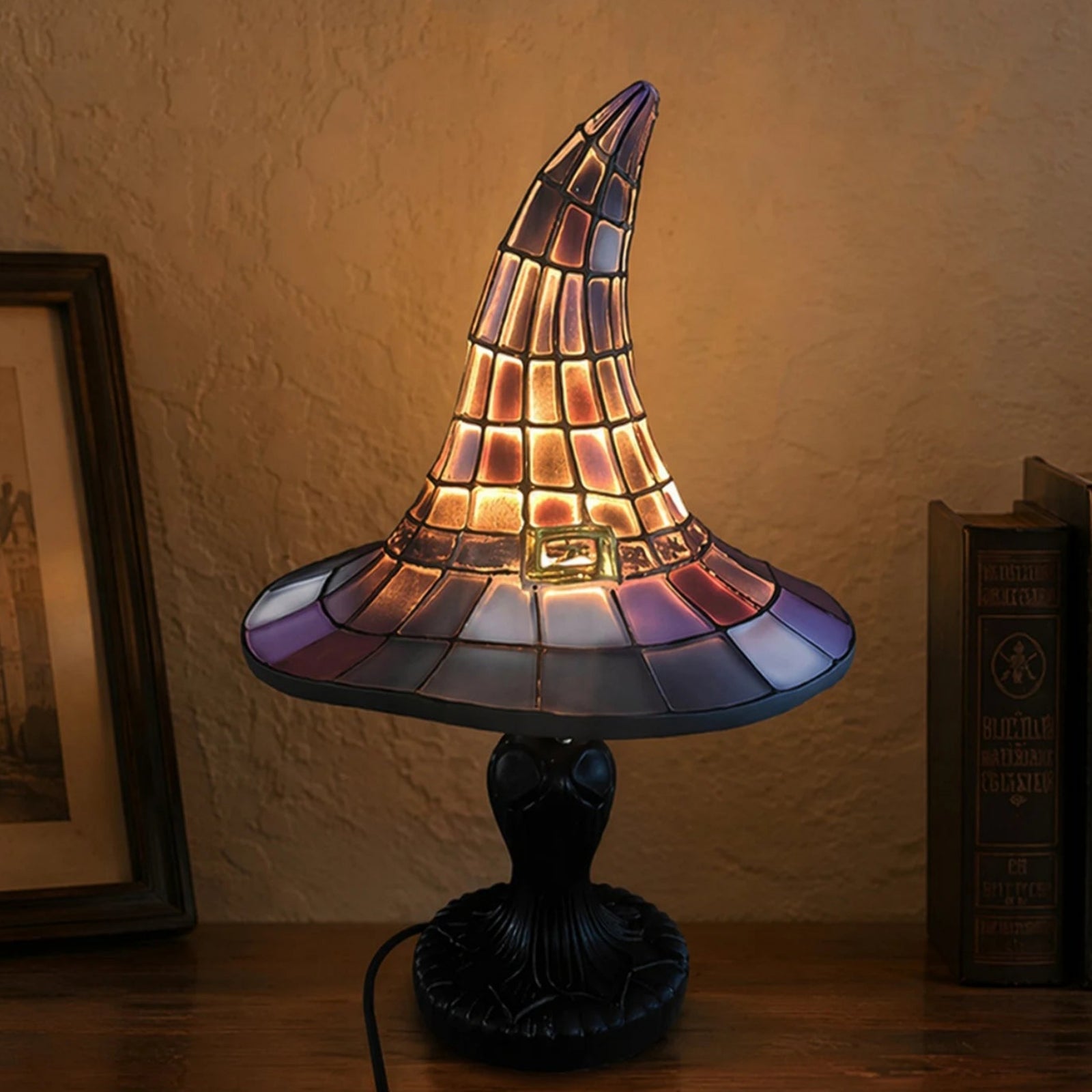 Stained glass witch hat night light on nightstand with framed picture and books