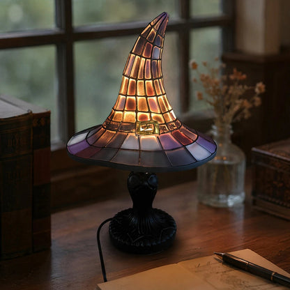 Witch hat night light on desk by window with pen and open book