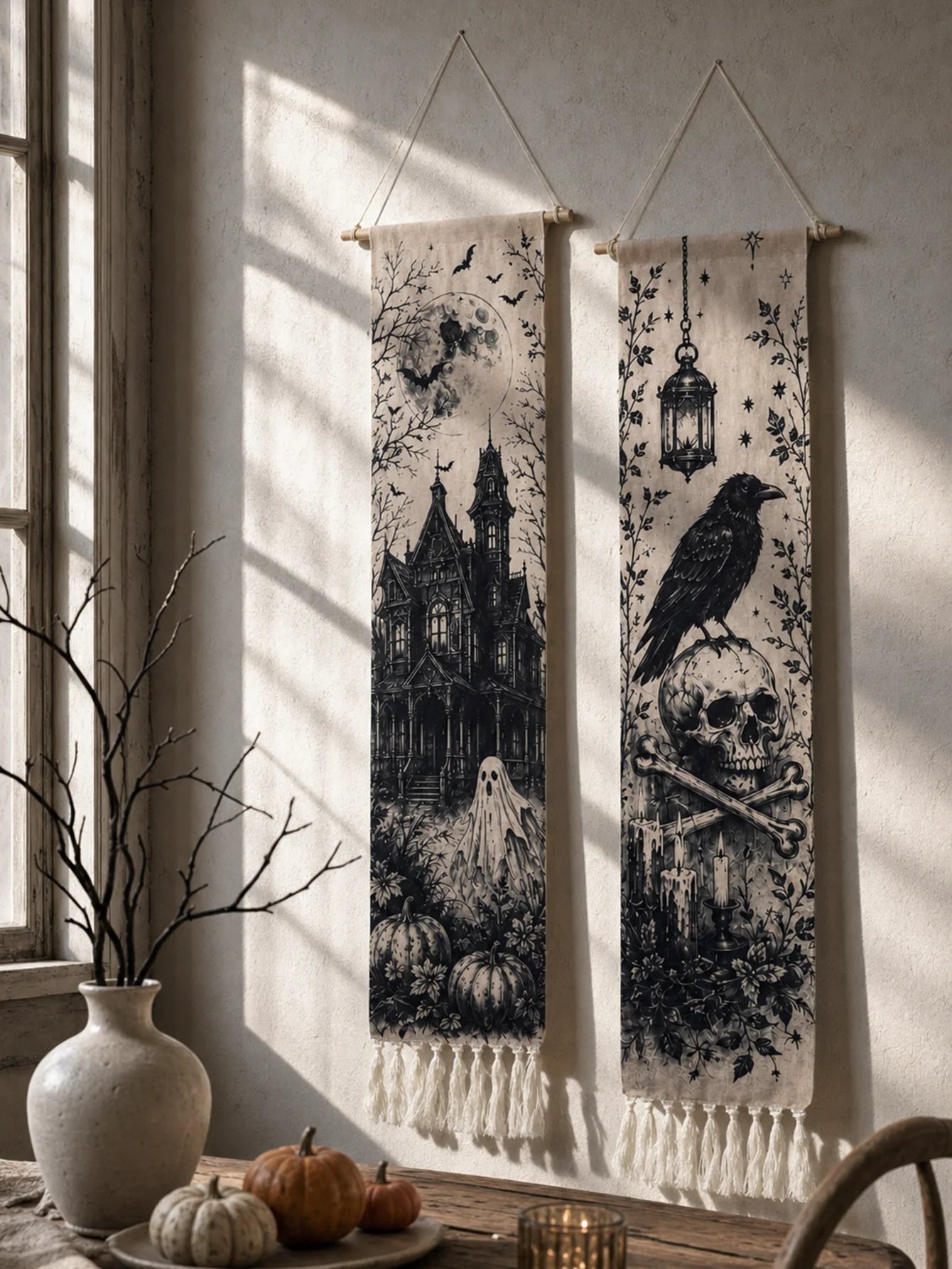 Halloween haunted house and crow skull tapestries hanging in window with pumpkins and vase