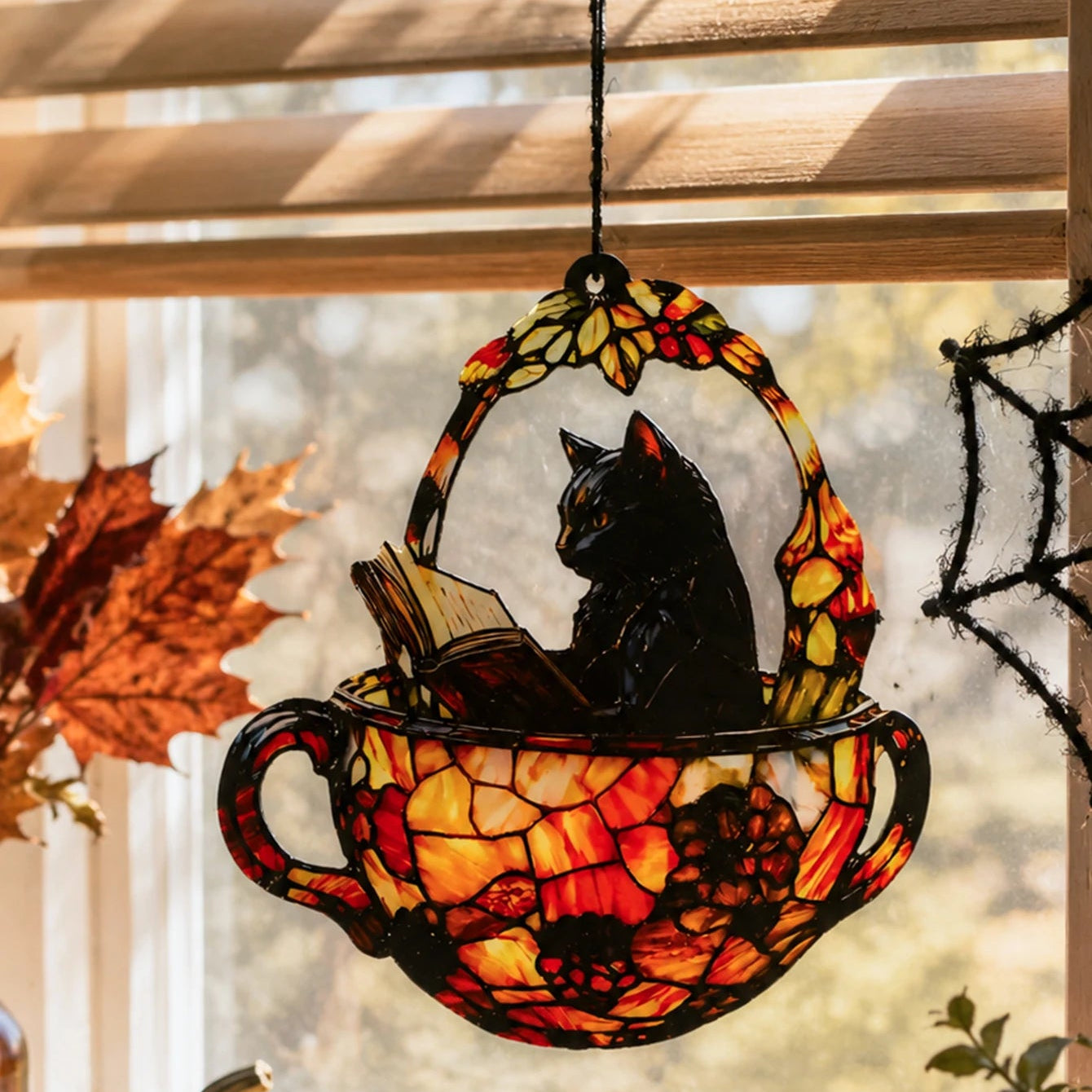Halloween black cat teacup suncatcher near window blinds with autumn leaf decor