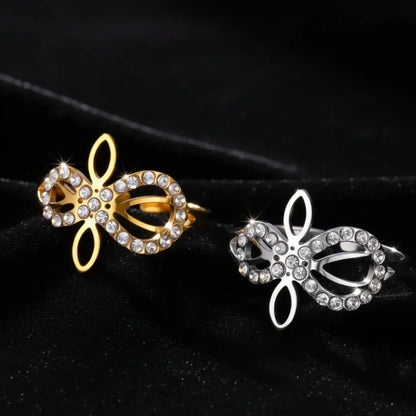 Gold and silver Infinity Celtic knot rings lying side by side on black velvet, side profile view of the open eternal-knot band