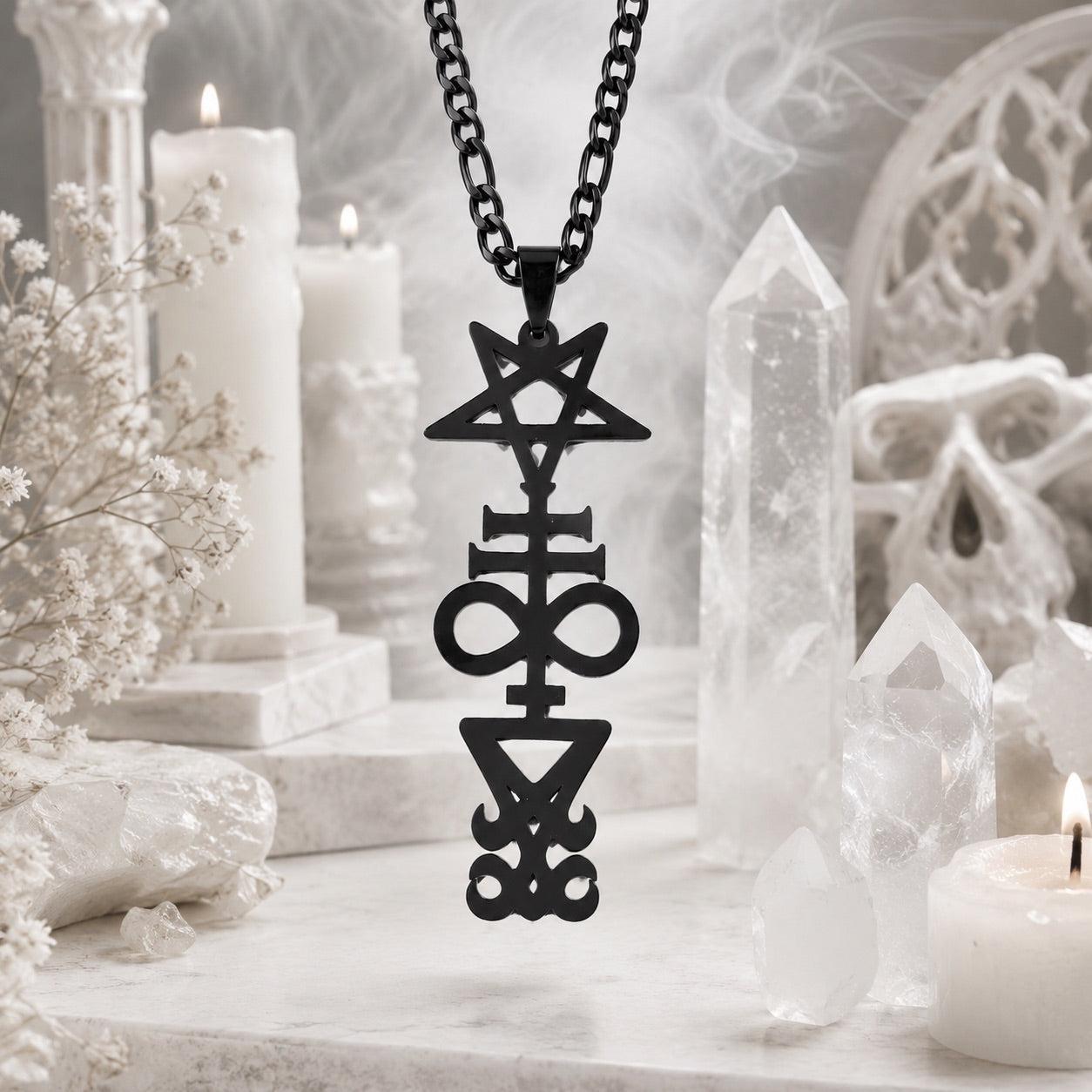 Black Inverted Pentagram Cross sigil pendant necklace on black chain, styled with white candles, quartz crystal points, dried flowers, and a small skull