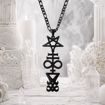 Black Inverted Pentagram Cross sigil pendant necklace on black chain, hanging in front of white marble pillars with a candle and quartz crystal points