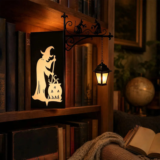 Iron witch silhouette bookend lamp glowing on gothic library bookshelf
