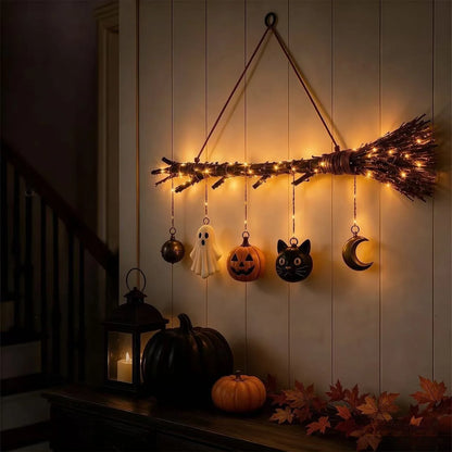 Lit witch broom decor hanging on a front door