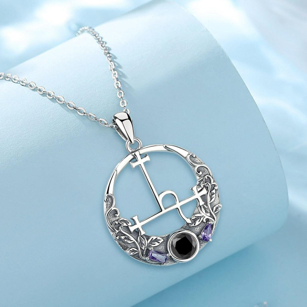 Sterling silver Lilith Sigil Wiccan necklace with a round pendant, intricate leaf details, purple gems, and a black stone.