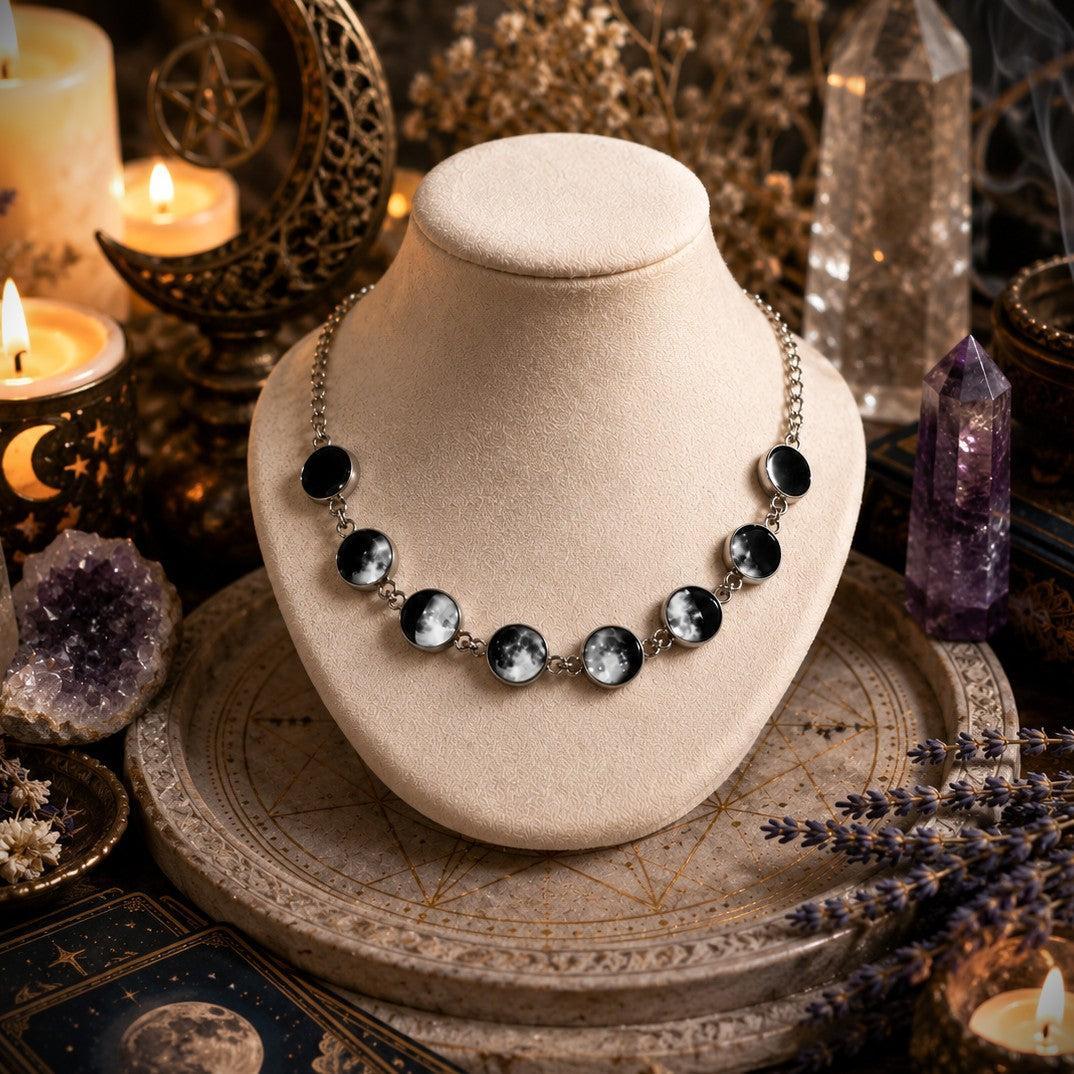 Silver gothic moon phase choker with black and white lunar cycle pendants on a beige display.