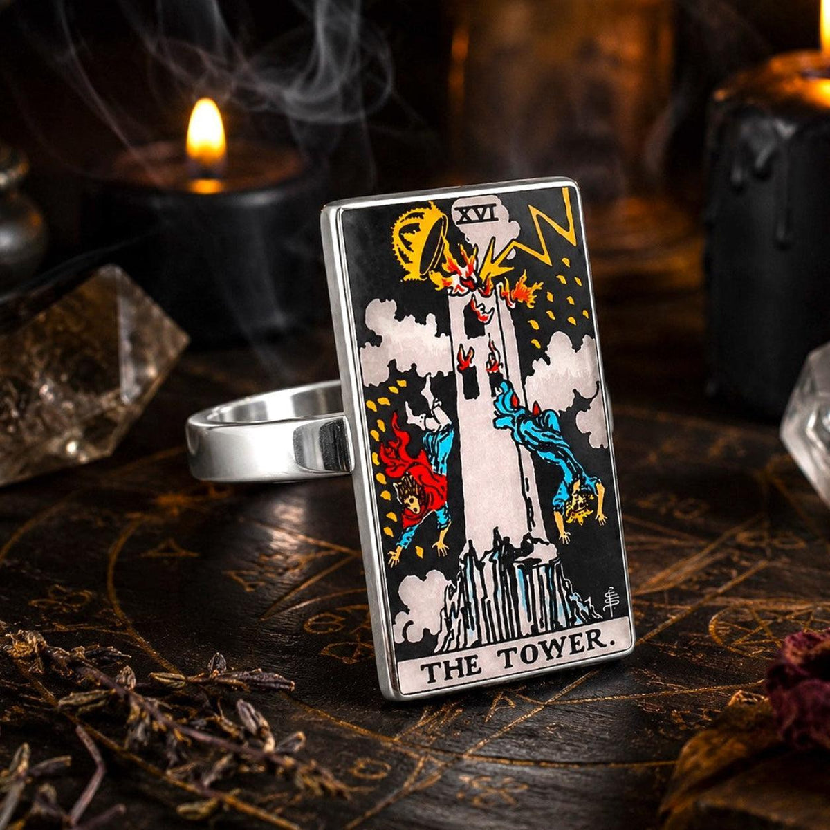 The Tower tarot card ring in stainless steel on a dark altar with candlelight and quartz crystals