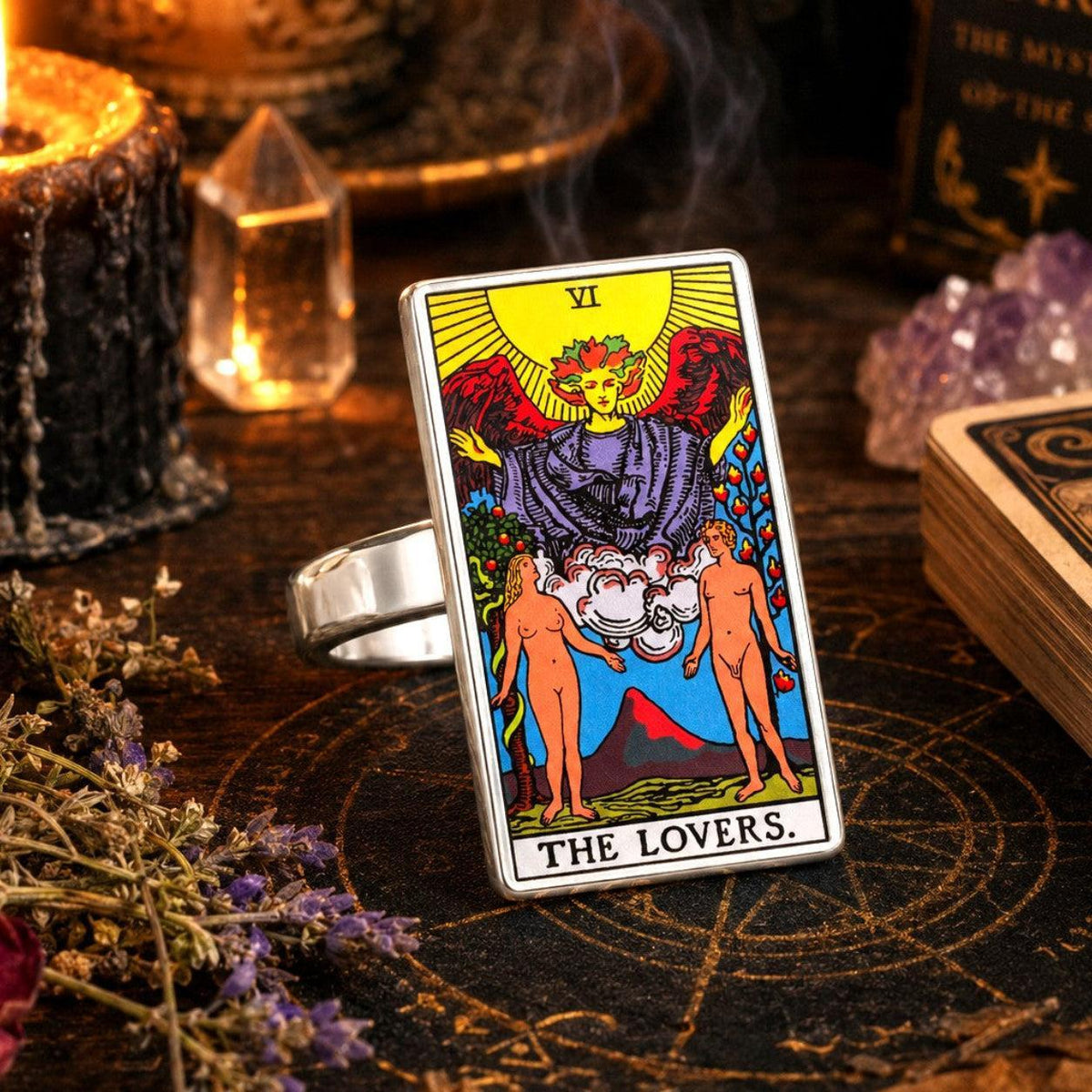 The Lovers tarot card ring in stainless steel with candles, amethyst and a tarot deck on dark wood