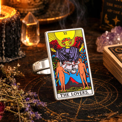 The Lovers tarot card ring in stainless steel with candles, amethyst and a tarot deck on dark wood